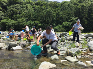 緑区長が稚鮎を放流する様子の写真